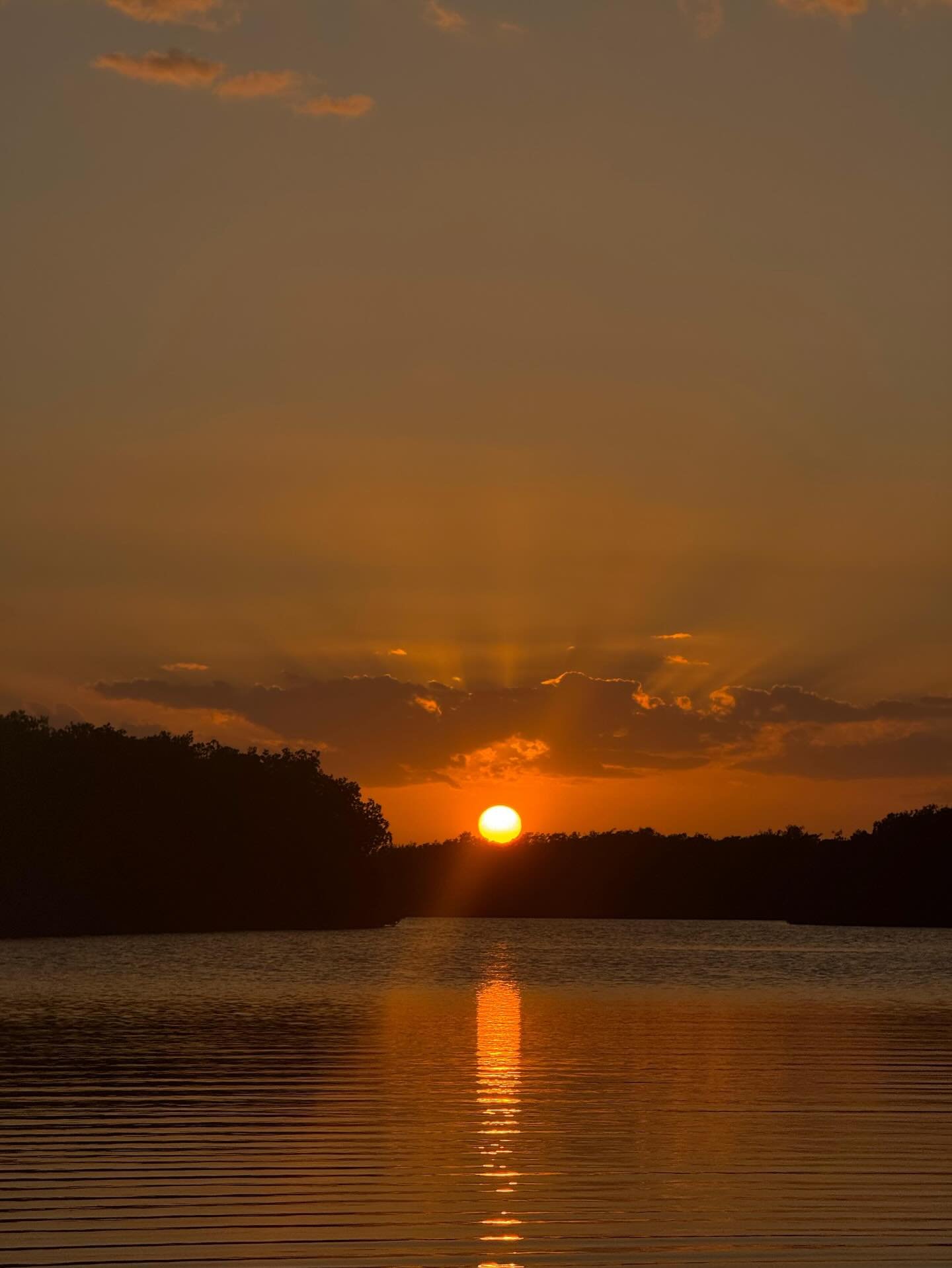 Amanecer sobre el estuario de manglar de Chelem con cielo anaranjado reflejado en el agua plana — el escenario de la salida de paddleboard de las 5:10 am en Progreso