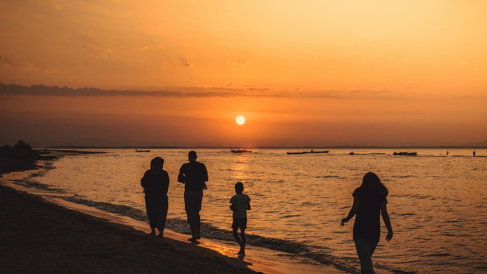 People walking along the seashore at sunset